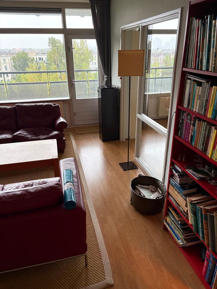 Woonkamer van een appartement in Den Haag voor de woningontruiming, met banken, boekenkast en vloerkleed