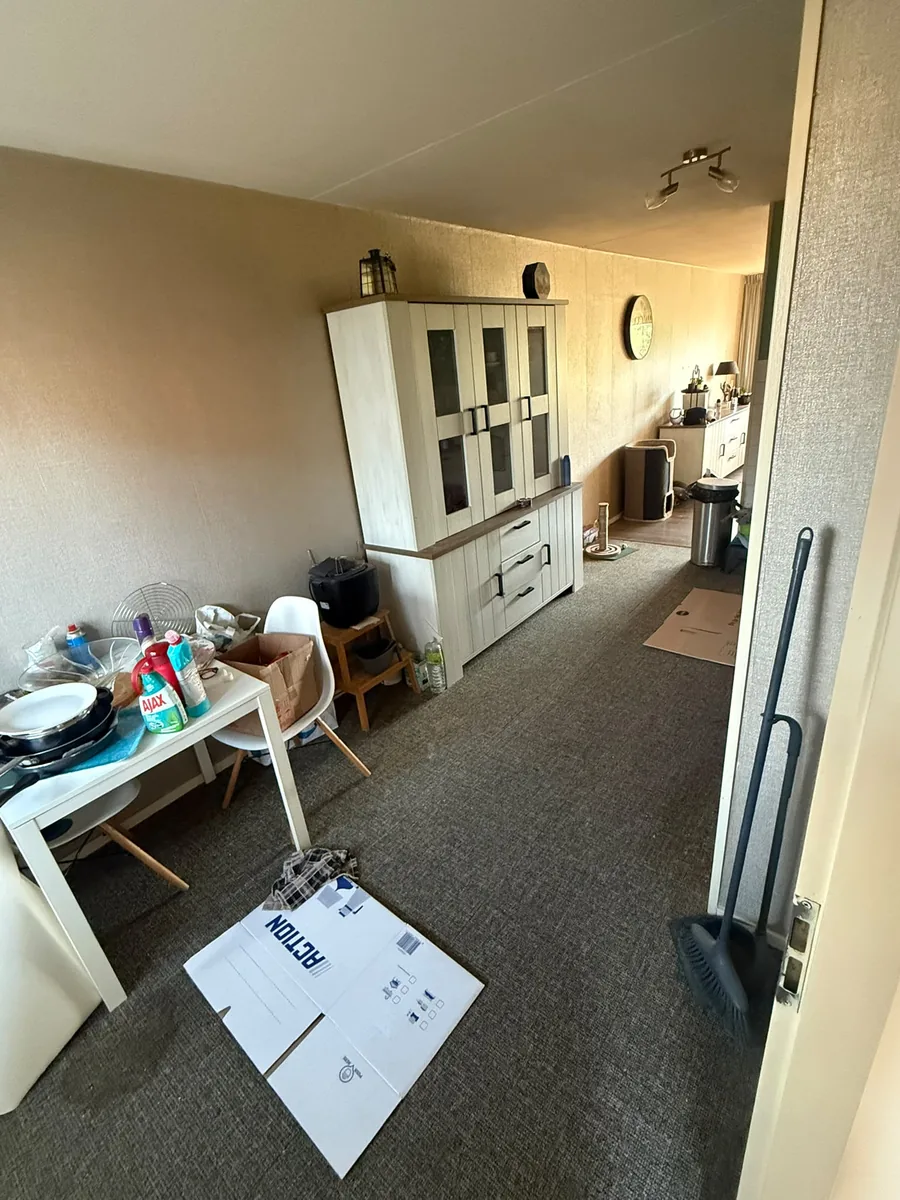 Tweede kamer in Vlaardingen voor de ontruiming, met buffetkast, tafel en huisraad