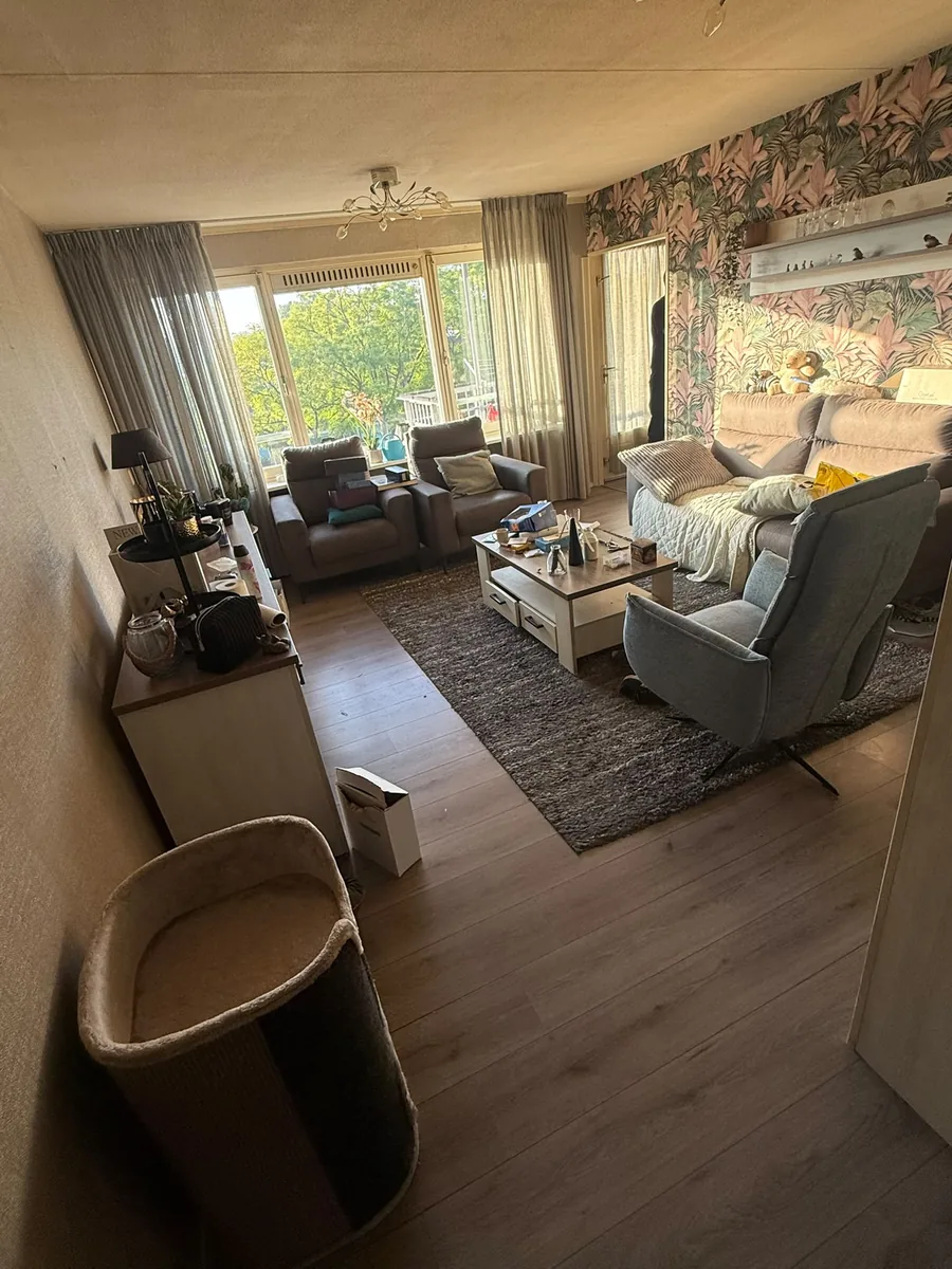 Woonkamer in Vlaardingen voor de ontruiming, met fauteuils, bank en salontafel