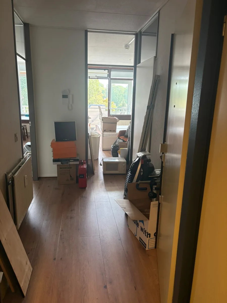 Hal in Voorburg voor de ontruiming, met verhuisdozen, magnetron en huisraad