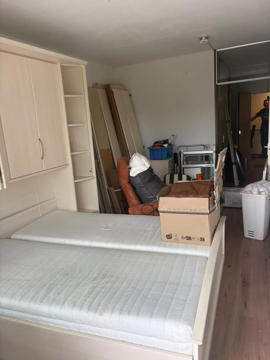 Slaapkamer in Voorburg voor de ontruiming, met bed en gedemonteerde kastdelen