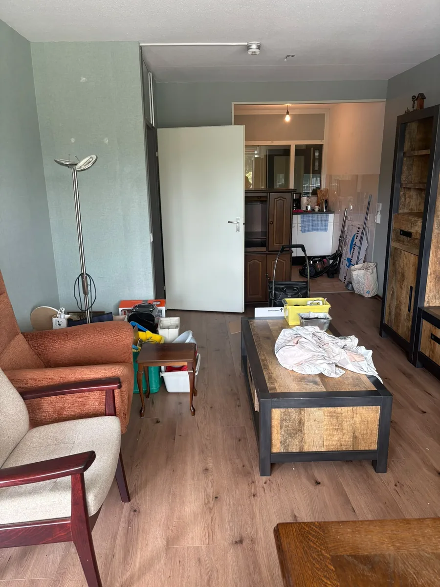 Woonkamer in Voorburg voor de ontruiming, met fauteuils, salontafel en kasten